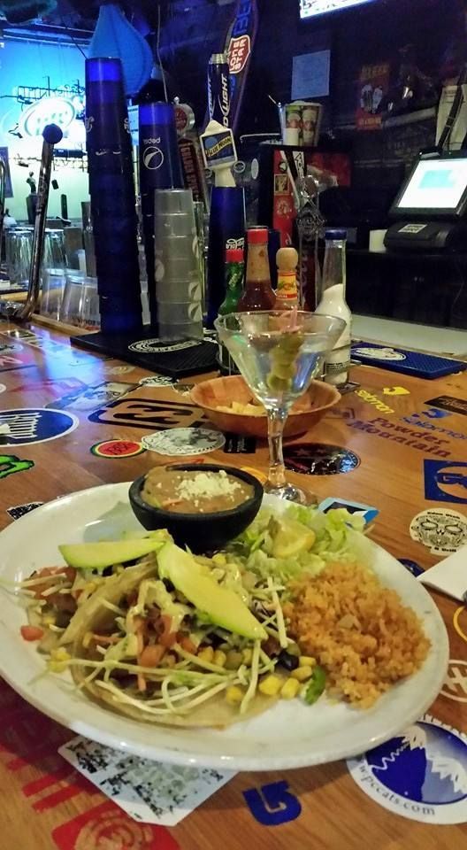 A plate of food and a martini on a table in a bar.