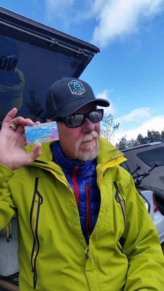 A man in a green jacket and hat is holding a fishing license.