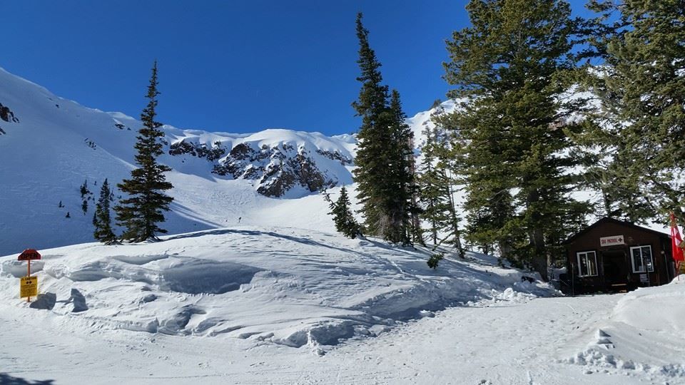 A cabin is sitting in the middle of a snowy mountain.