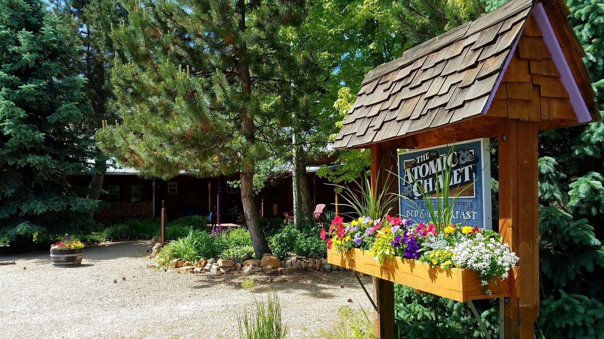 A wooden sign with flowers on it is in front of a building.