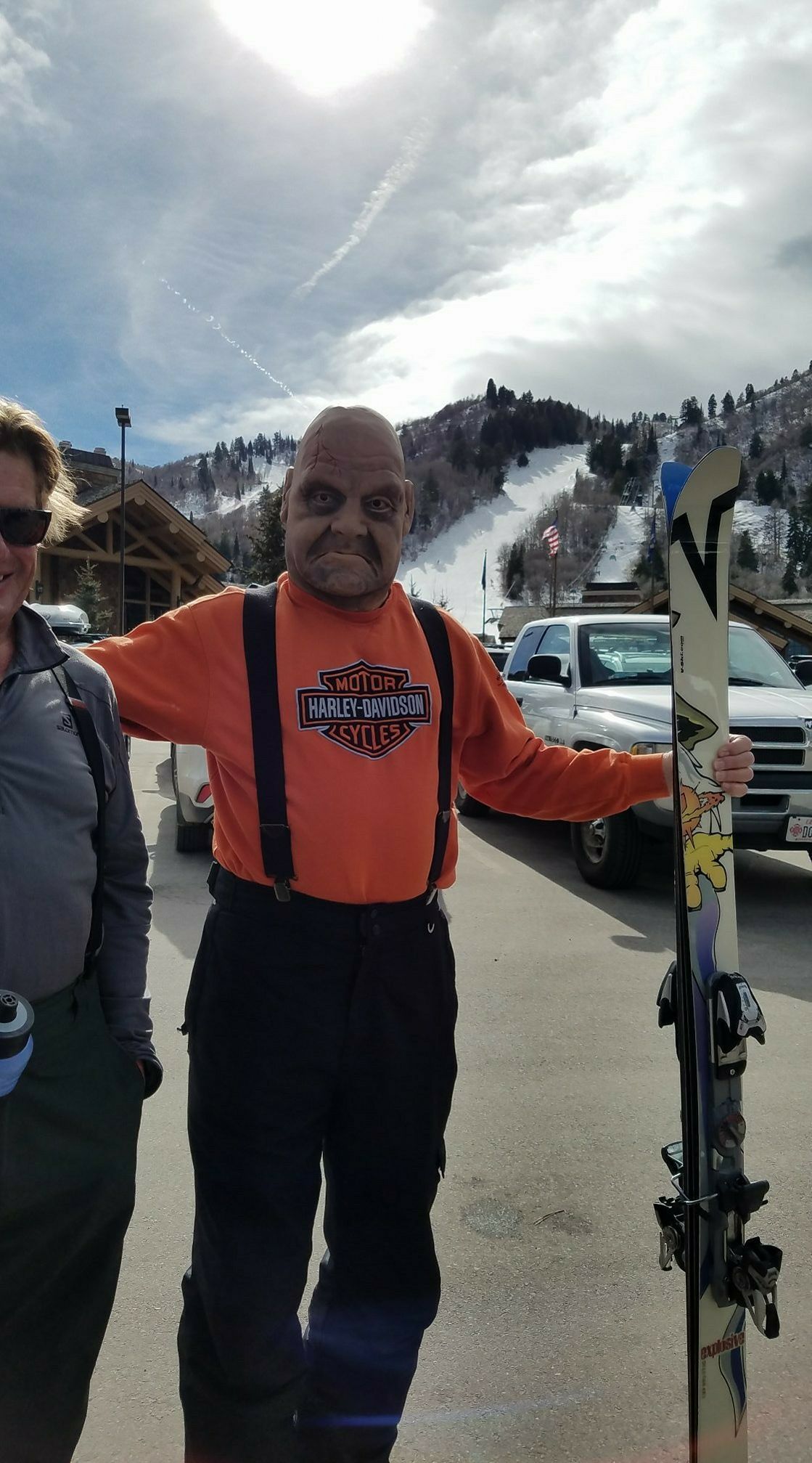 A man in a harley davidson shirt is holding a pair of skis.