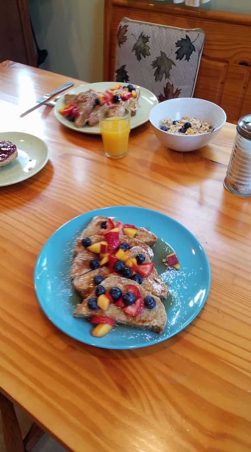 A wooden table topped with plates of food and a bowl of cereal.