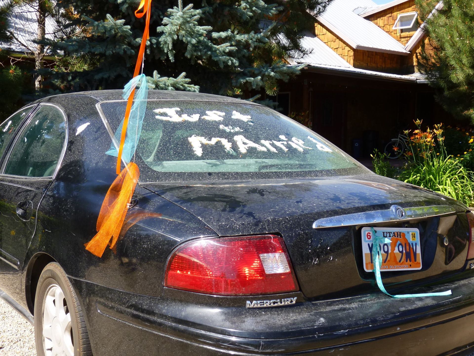 A black car with a sign on the windshield that says just married