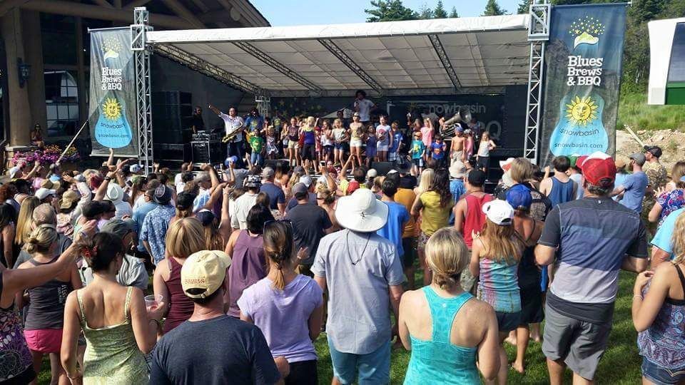 A large crowd of people are standing in front of a stage at a concert.