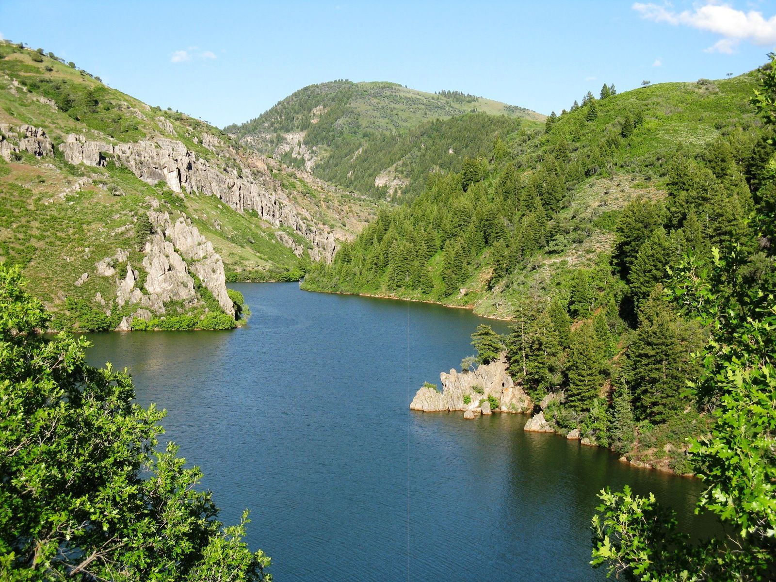 A lake surrounded by mountains and trees on a sunny day