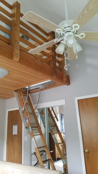 A room with a ceiling fan and a ladder