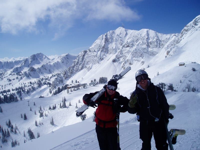 Two people standing on top of a snow covered mountain