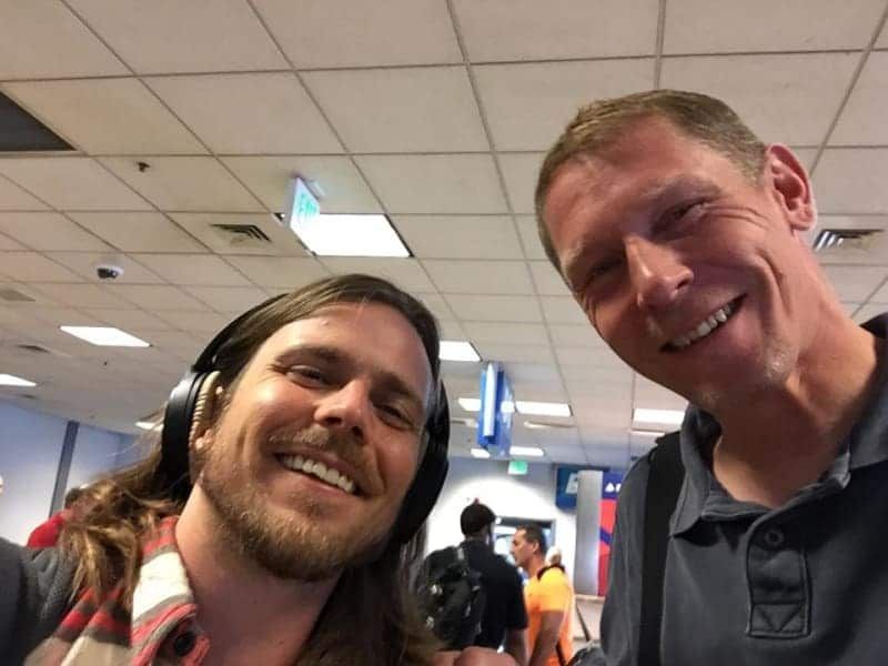 Two men wearing headphones are posing for a picture