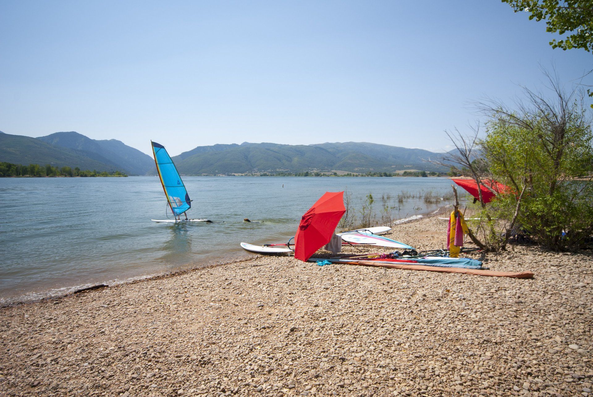 A beach with umbrellas and a sailboat in the water