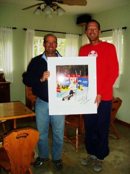 A man in a red shirt holds a framed picture of a hockey game