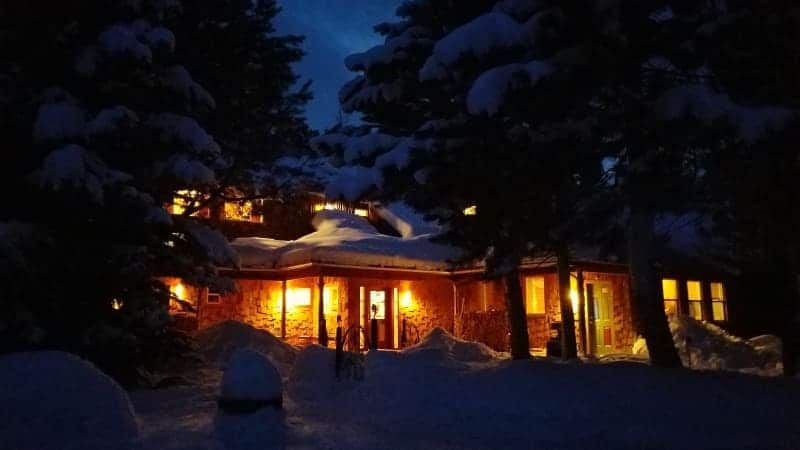 A house is lit up in the snow at night