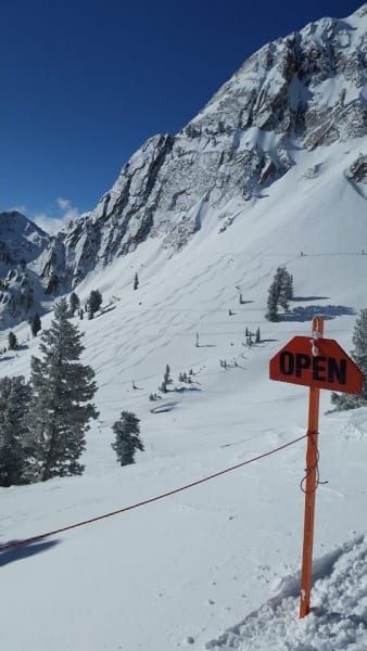 A snowy mountain with an open sign in the foreground