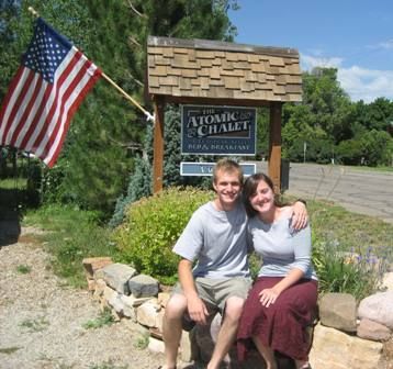 A man and woman pose in front of a sign for the atomic chalet