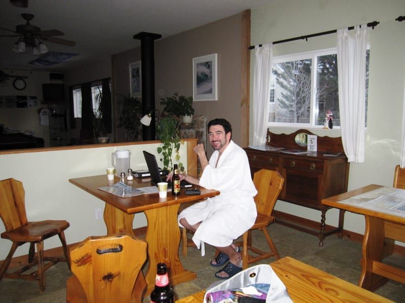 A man in a bathrobe sits at a table with a laptop
