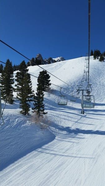 A ski lift going up a snow covered mountain