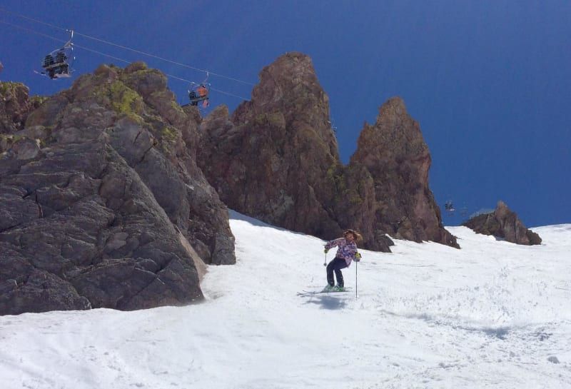 A person is riding a snowboard down a snow covered slope.