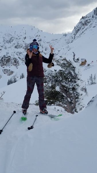 A person is standing in the snow on skis.