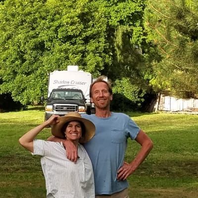 A man and a woman are posing for a picture in front of a rv.