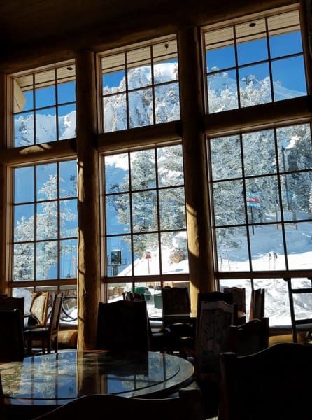 A room with a lot of windows looking out to a snowy mountain