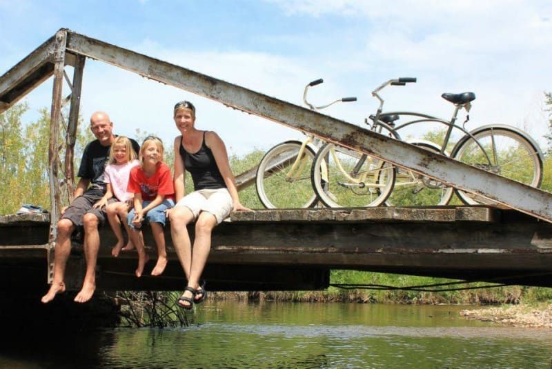A family is sitting on a bridge over a river.
