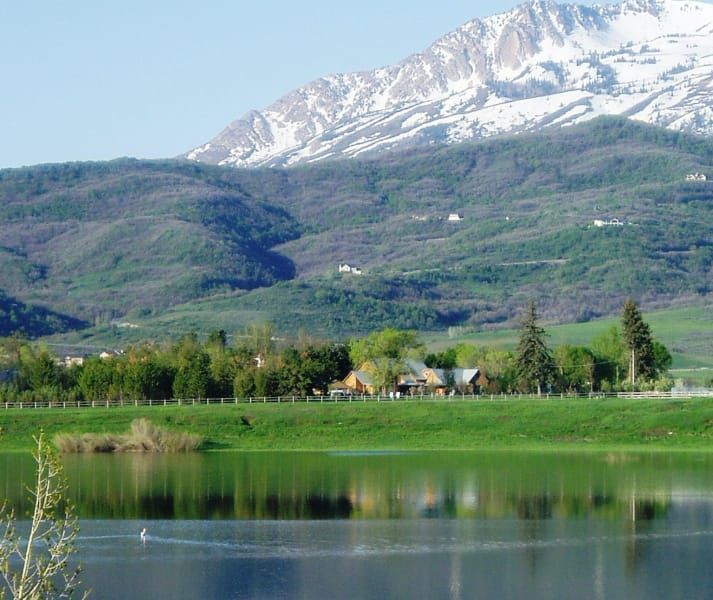 A lake with mountains in the background and a house in the foreground