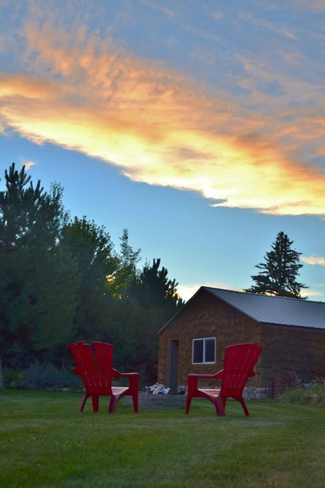 Two red chairs are sitting in front of a house at sunset