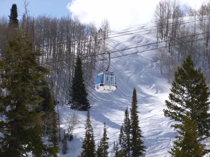 A ski lift is going down a snowy mountain