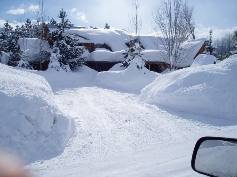 A snowy driveway with a house in the background