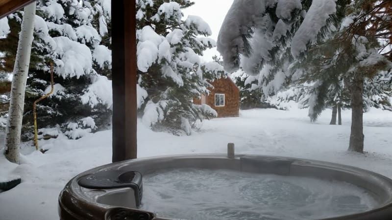 A hot tub in the snow with trees in the background