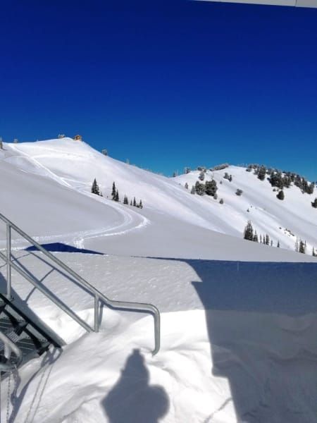 A shadow of a person is cast on a snowy mountain