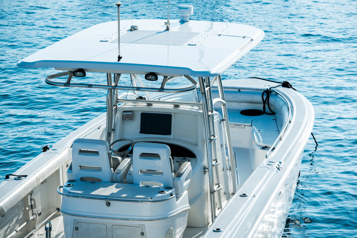 White motorboat on blue water, with a radar and two white seats under a canopy.