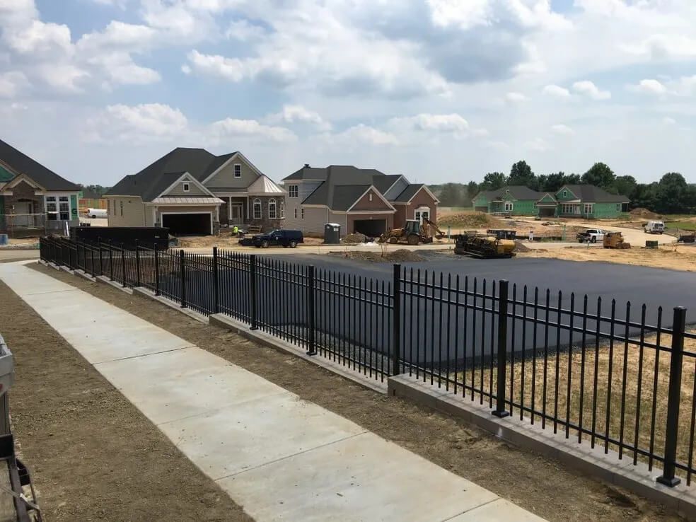 Cross-section of fence post installation. Brown fence post set in concrete; metal post also shown for support.