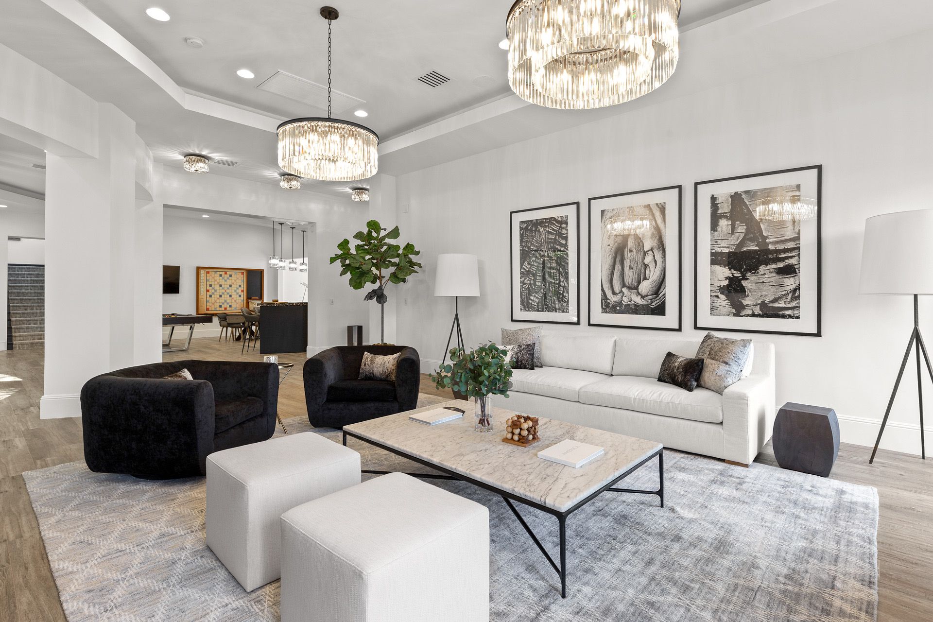 Living room with white walls, black furniture, and decorative chandeliers.