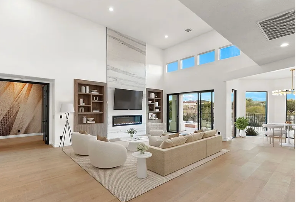 Modern living room with high ceilings, fireplace, and open floor plan with outdoor view.