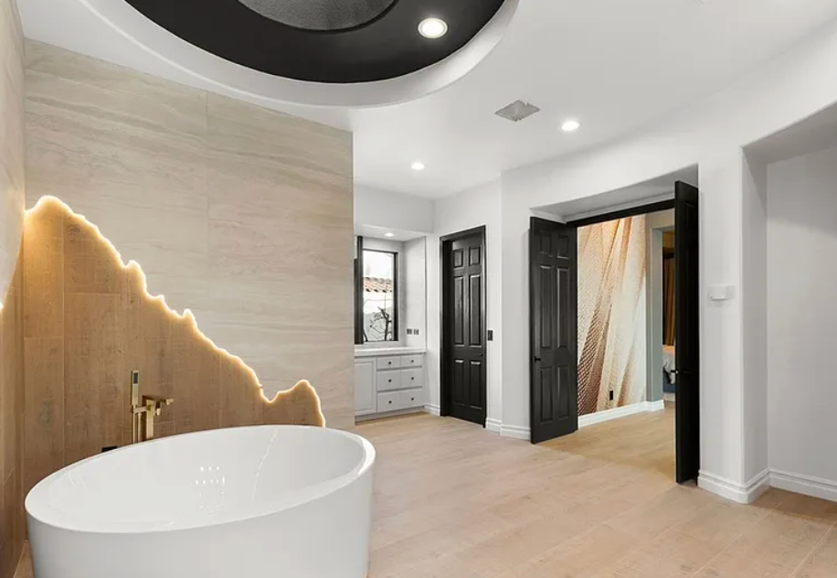 Modern bathroom with a bathtub, marble walls, and black doors.