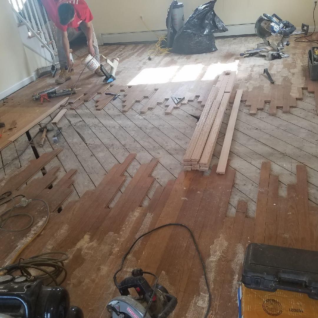 A man is working on a wooden floor in a room.