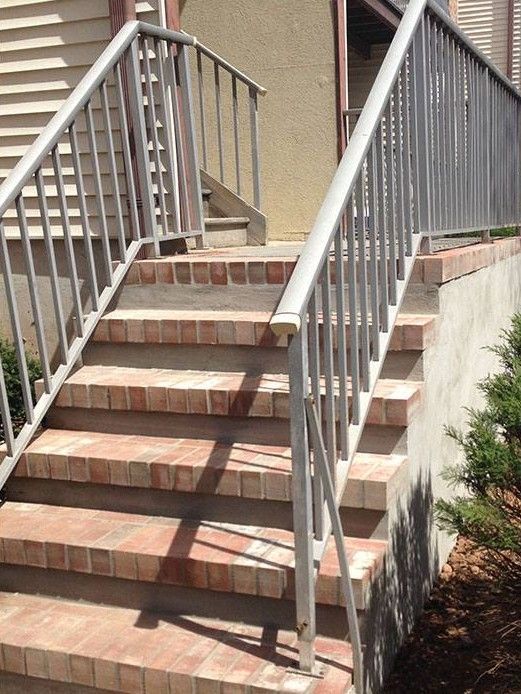 A set of stairs with a metal railing and brick steps