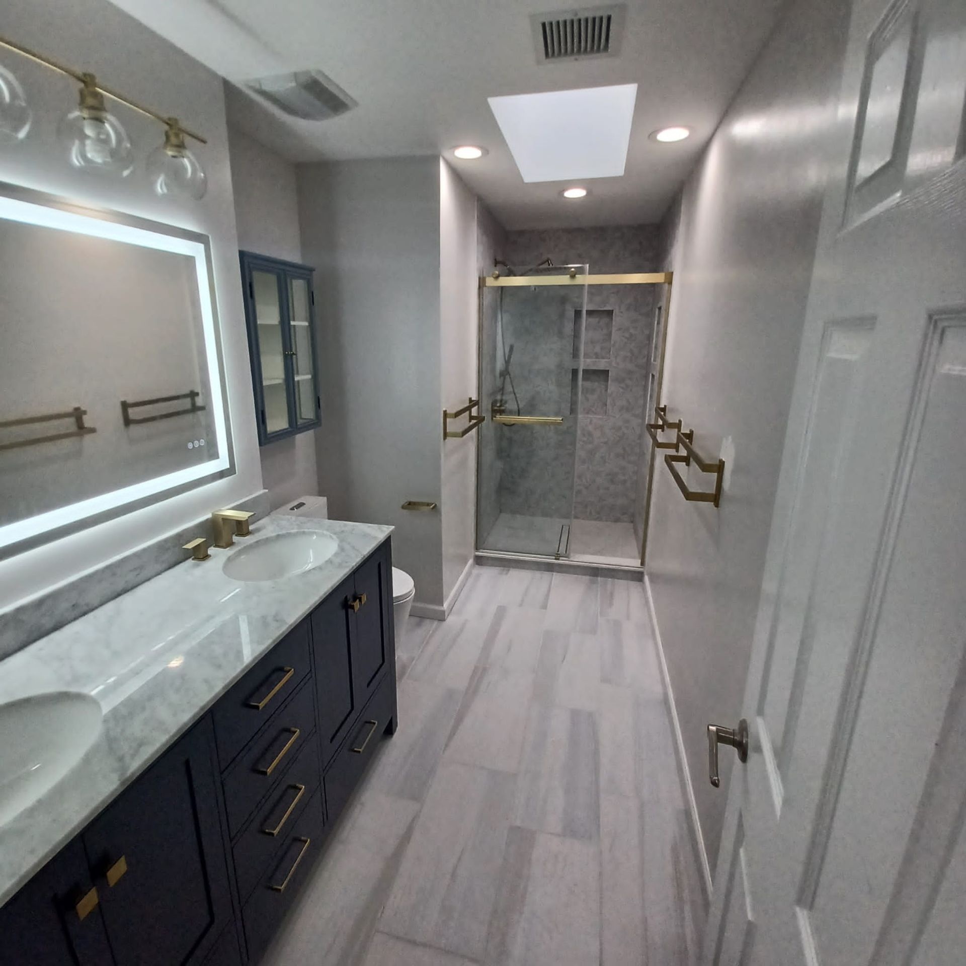 A bathroom with two sinks , a toilet , a shower and a mirror.