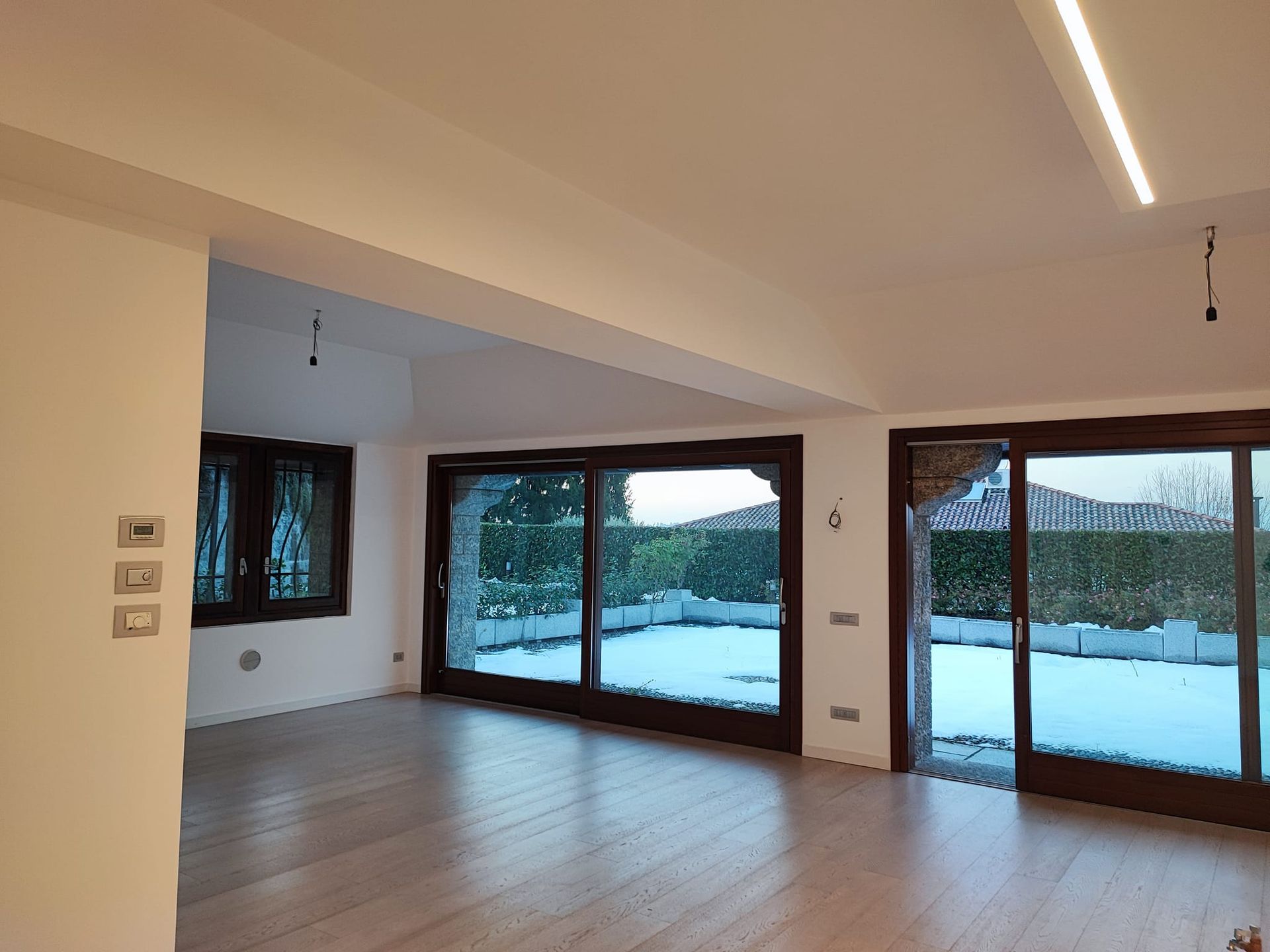 Interno di una stanza con ampie finestre che si affacciano su un cortile innevato.