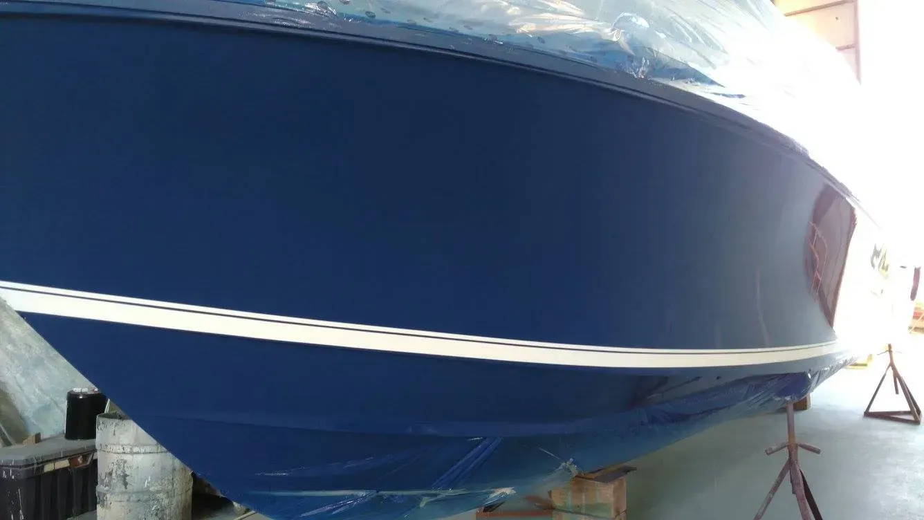 A blue boat is sitting on a stand in a warehouse.