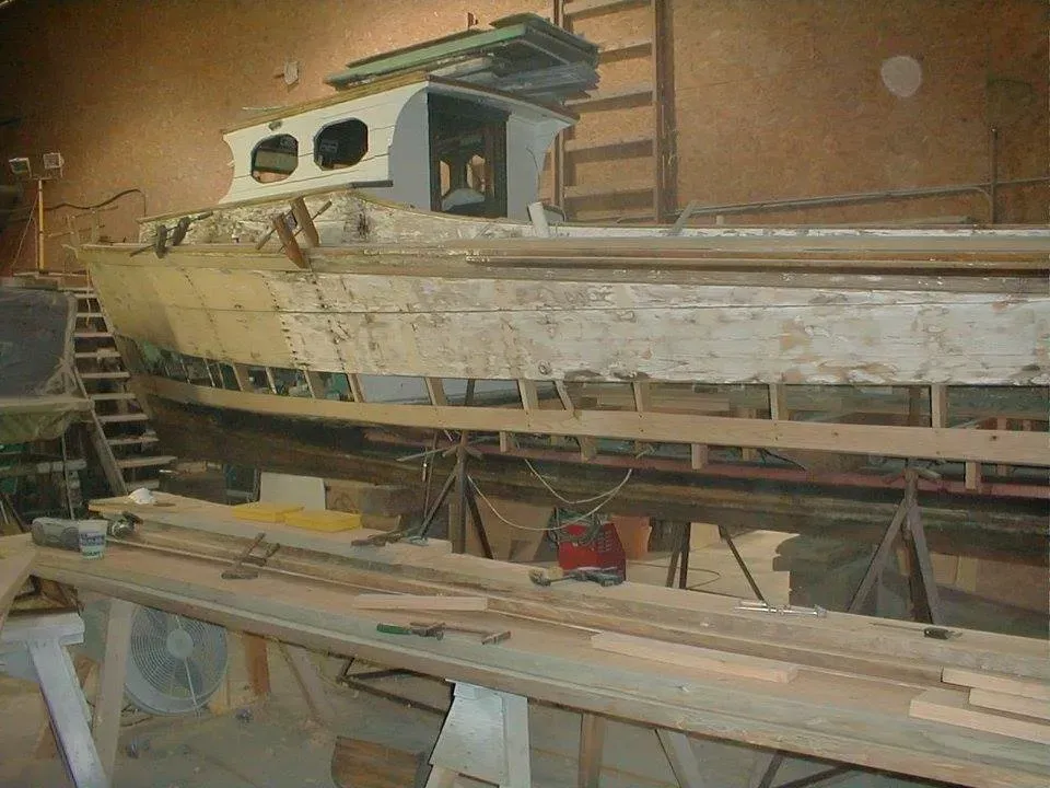 A wooden boat is being built in a warehouse.