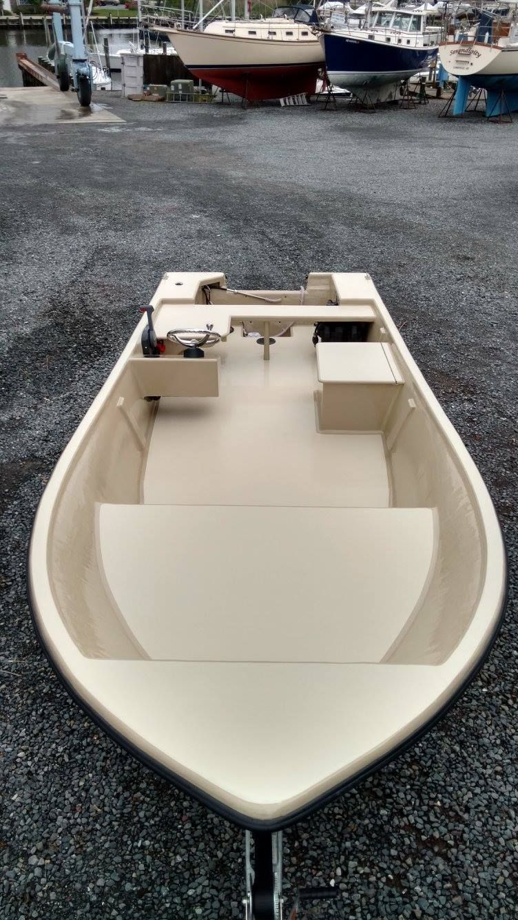 A small boat is parked in a gravel lot.