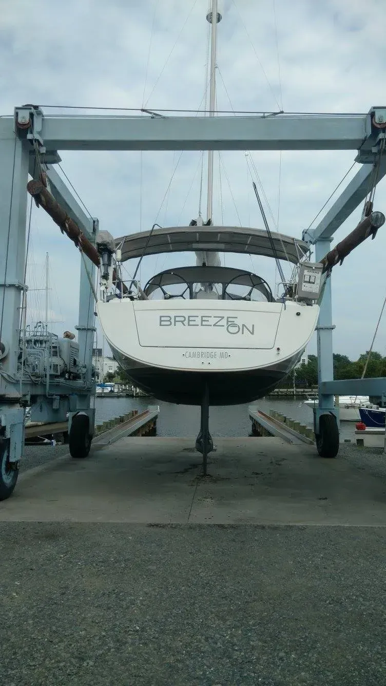 A boat is being lifted by a crane in a marina.