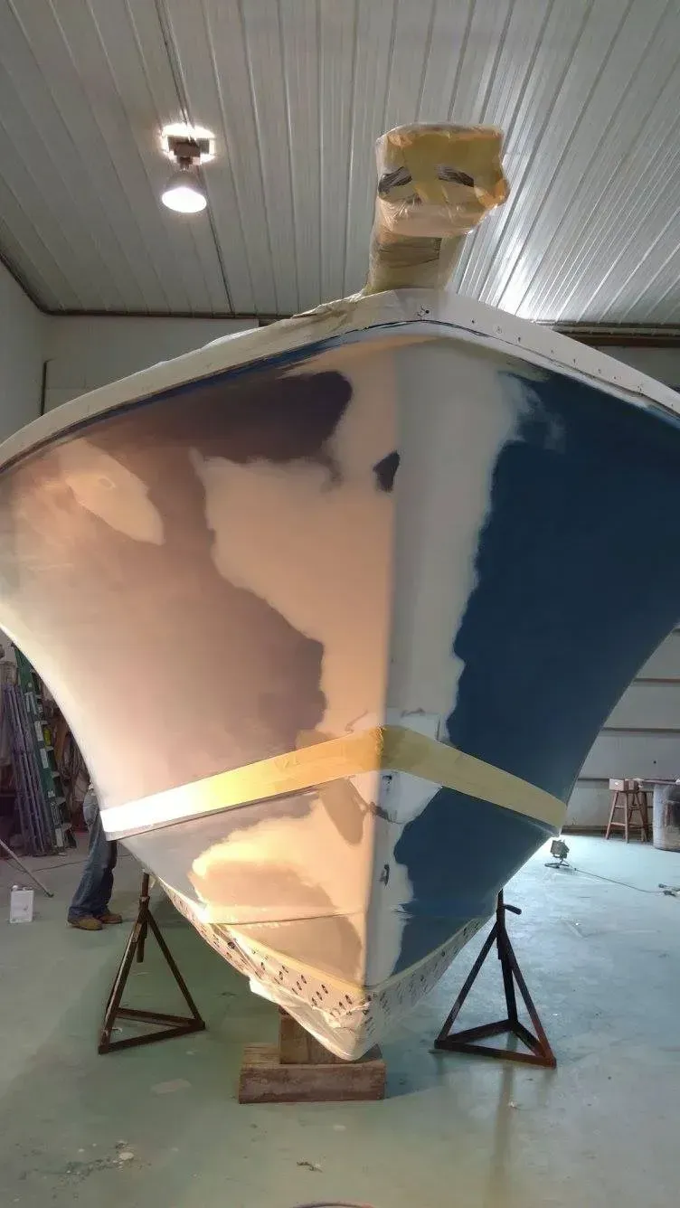 A boat is being painted in a warehouse.