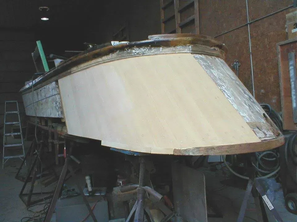 A wooden boat is being built in a garage.