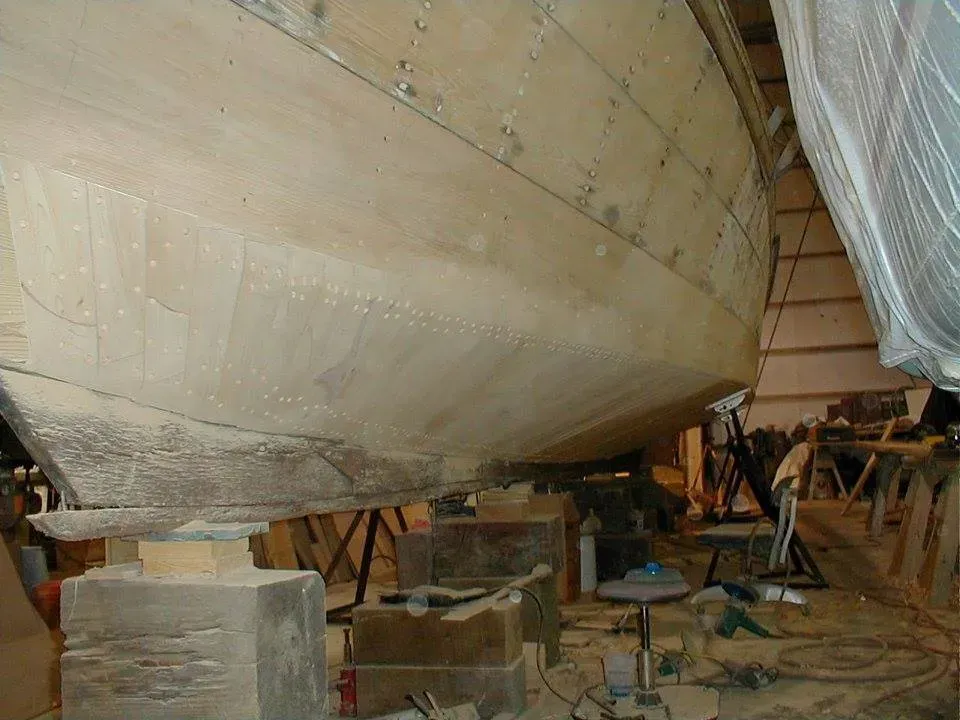 A wooden boat is being built in a factory