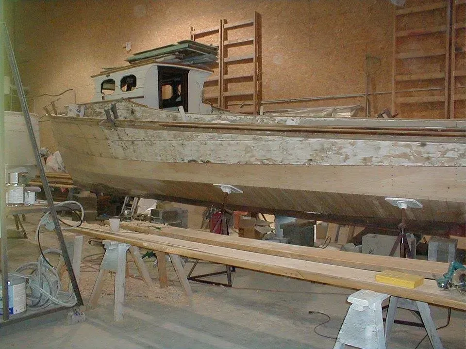 A wooden boat is being built in a workshop.