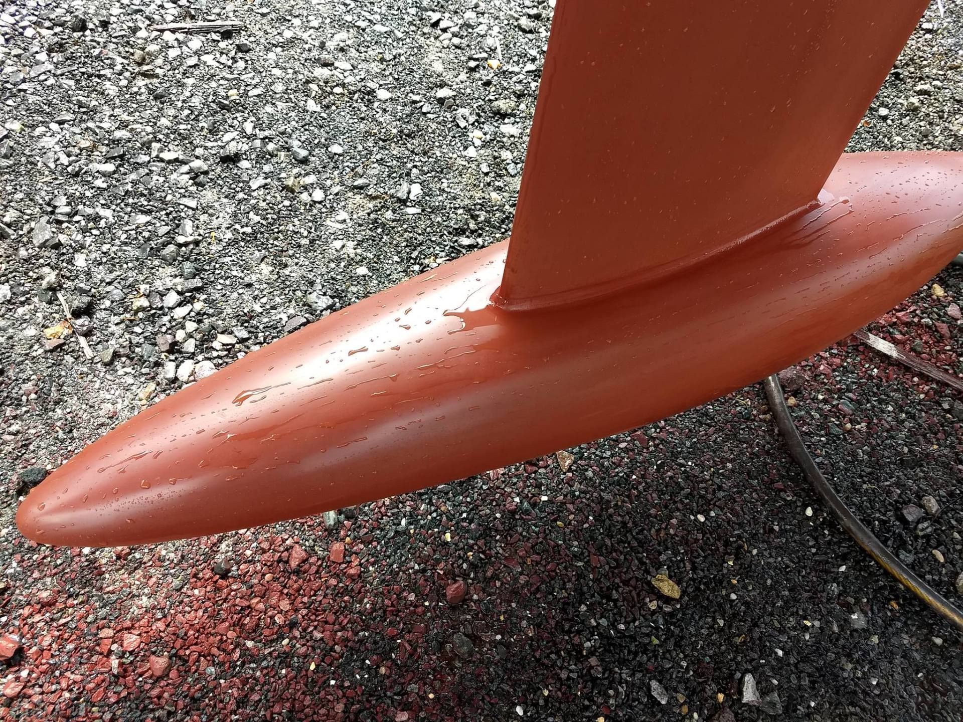 A close up of a surfboard fin on the ground.