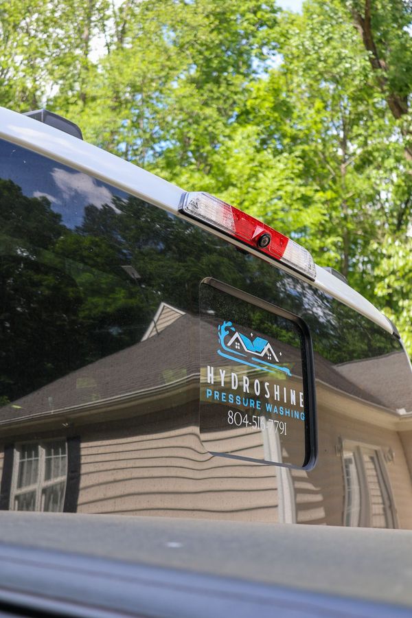 A close up of the back window of a truck with a house in the background.