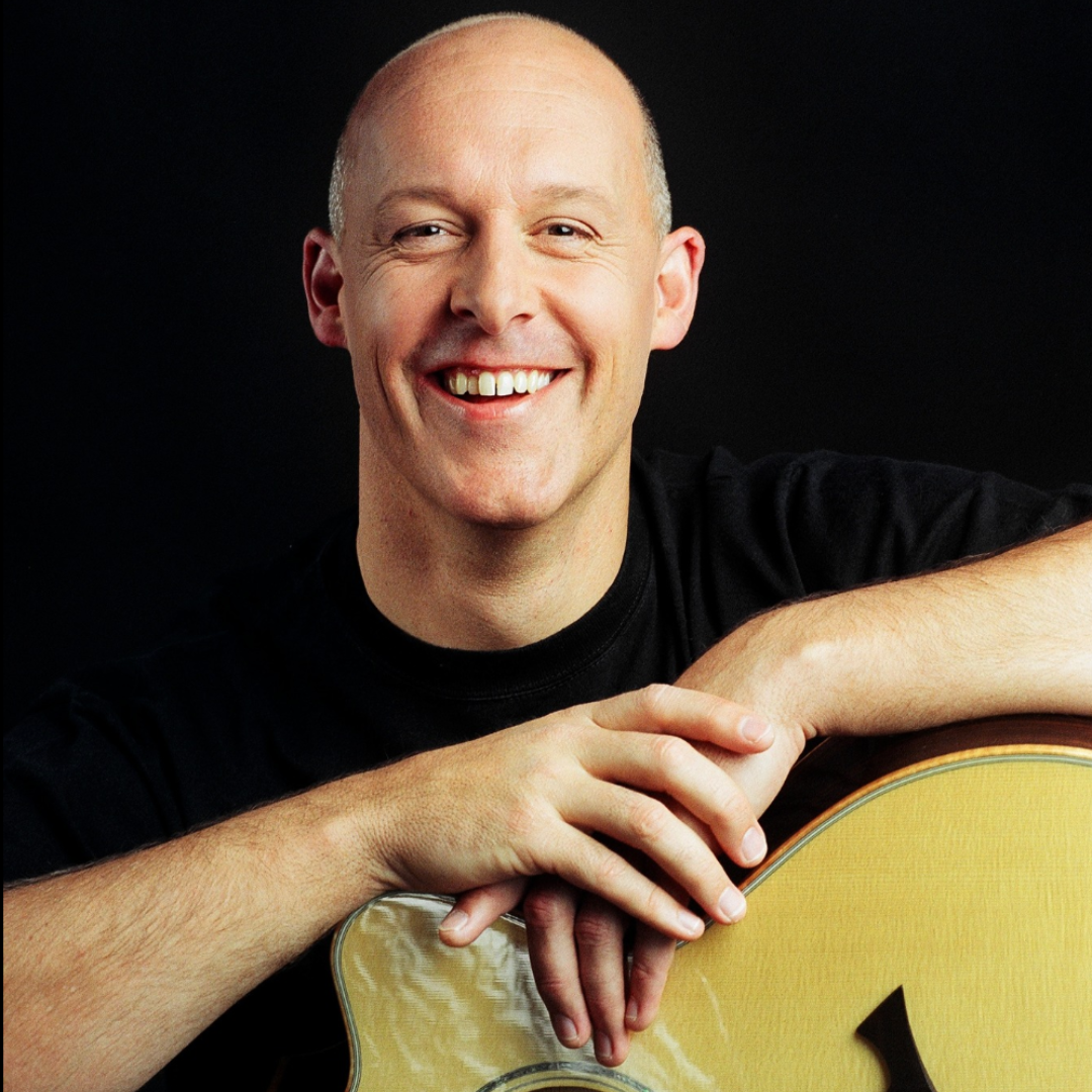 A Man in A Black Shirt Is Smiling While Holding a Guitar — Chop 'n Chill in Port Macquarie, NSW